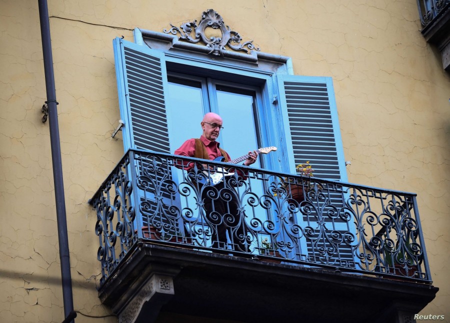 Gitárral egy idősebb ember a balkonon Olaszországban. Fotó: Reuters