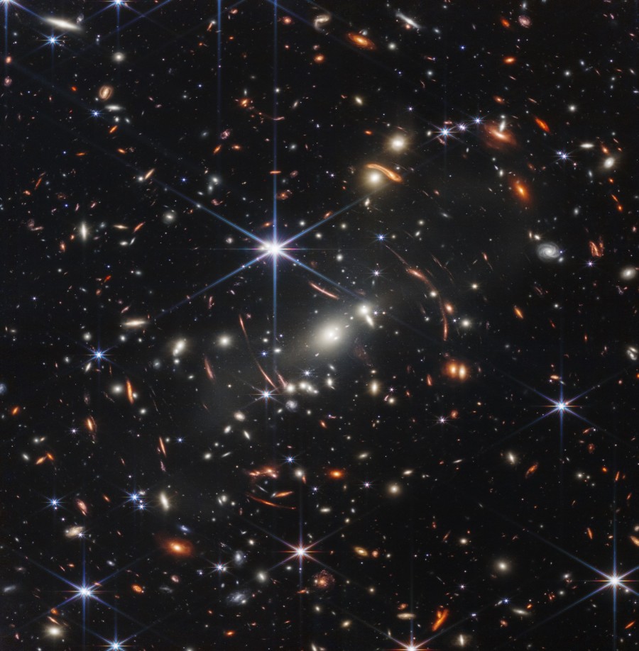 A SMACS 0723 galaxishalmaz 4,6 milliárd évvel ezelőtt. A felvétel készítése közben a JWST elkapott egy 13,1 milliárd fényév távolságra lévő galaxisból származó fotonokat is. Ez a kép nagyjából akkor területet fed le az égből, mint amekkorát egy homokszem, ha kinyújtott karral tartjuk magunk elé. (Fotó: NASA, ESA, CSA, and STScI)