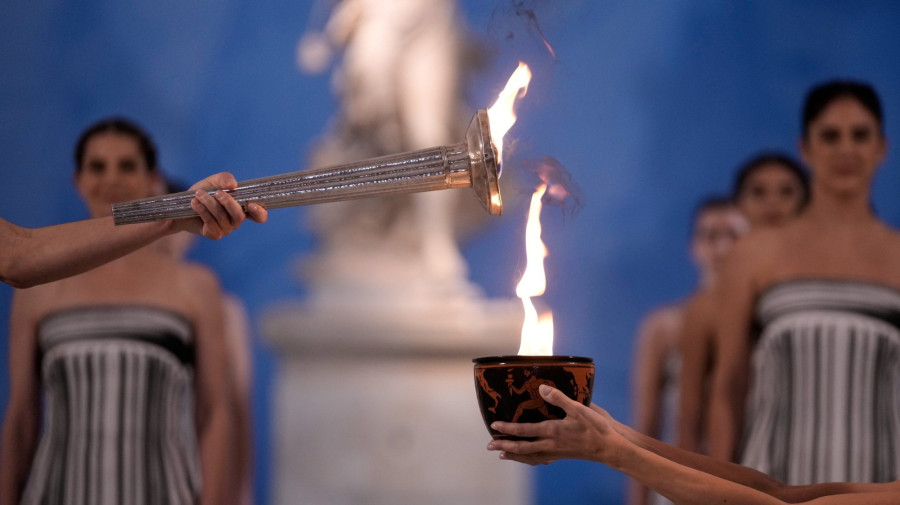 A fõpapnõ szerepét játszó Mary Mina görög színésznõ (b) meggyújt egy fáklyát az olimpiai láng fellobbantási ünnepségén az eredeti olimpiai játékok helyszínén, az ókori Olümpia Régészeti Múzeumában 2025. november 26-án. A 2026-os téli olimpiát február 6. és 22. között, a paralimpiát március 6. és 15. között rendezi Milánó és Cortina d'Ampezzo közösen. MTI/AP/Thanászisz Sztavrakisz